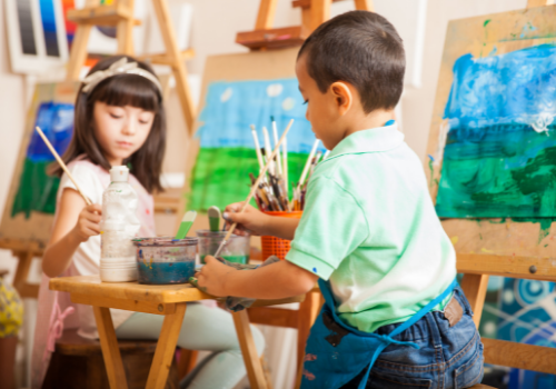 Two young children painting at easels