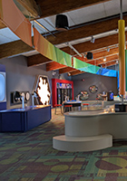 Interior shot with colorful rainbow signs hanging from the ceiling, a glowing snowflake, and other discovery stations visible.