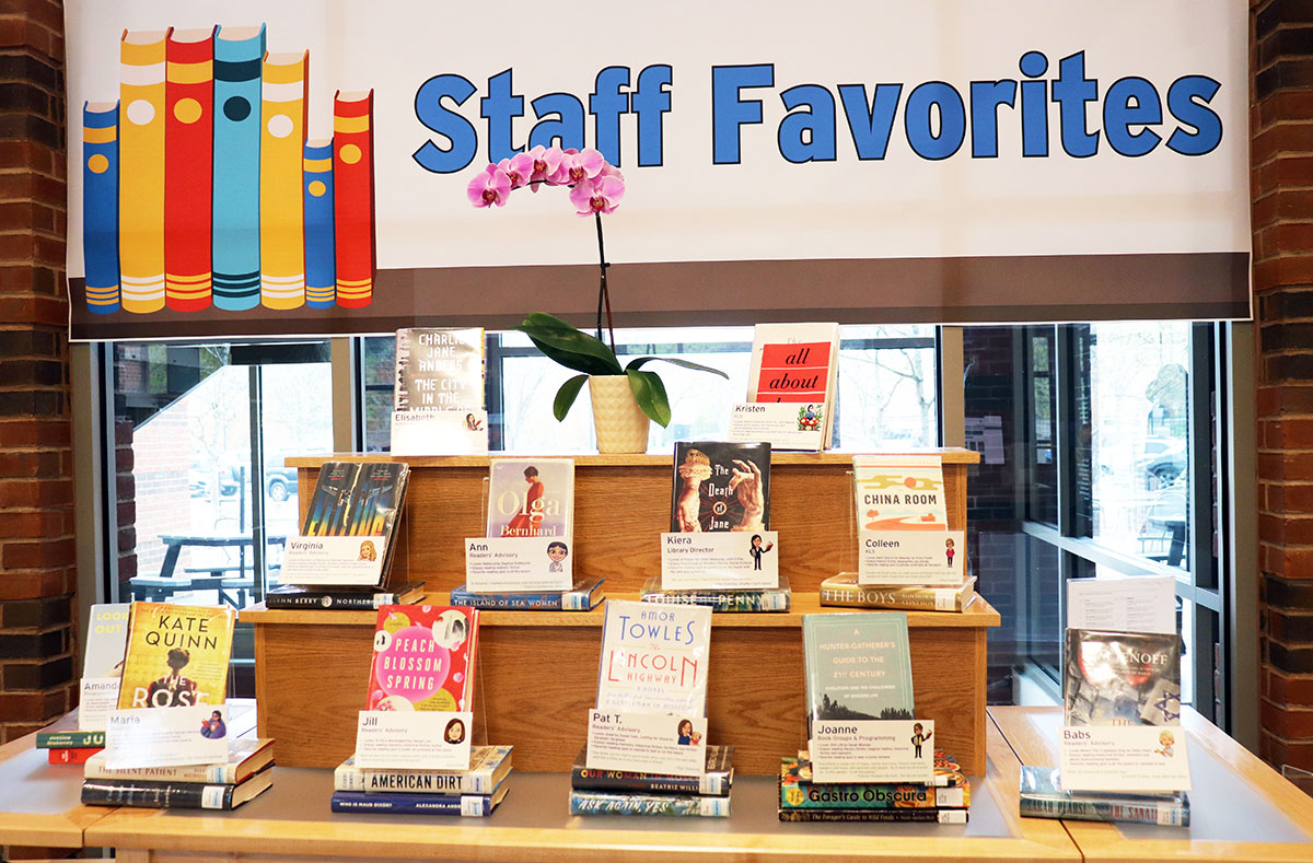 Display of books on a two-tiered table with a sign that says "Staff Favorites" in the back.