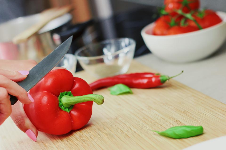 Woman's hand cutting a red pepper on cutting board