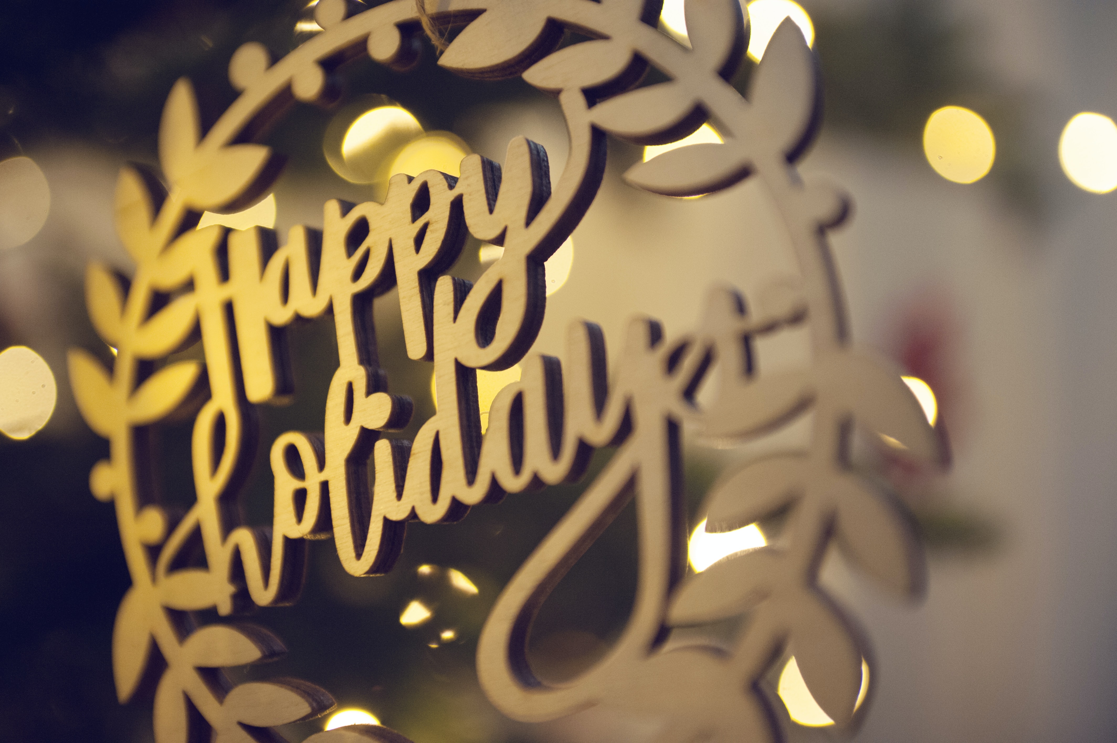close up of a holiday ornament that says happy holidays in gold lettering