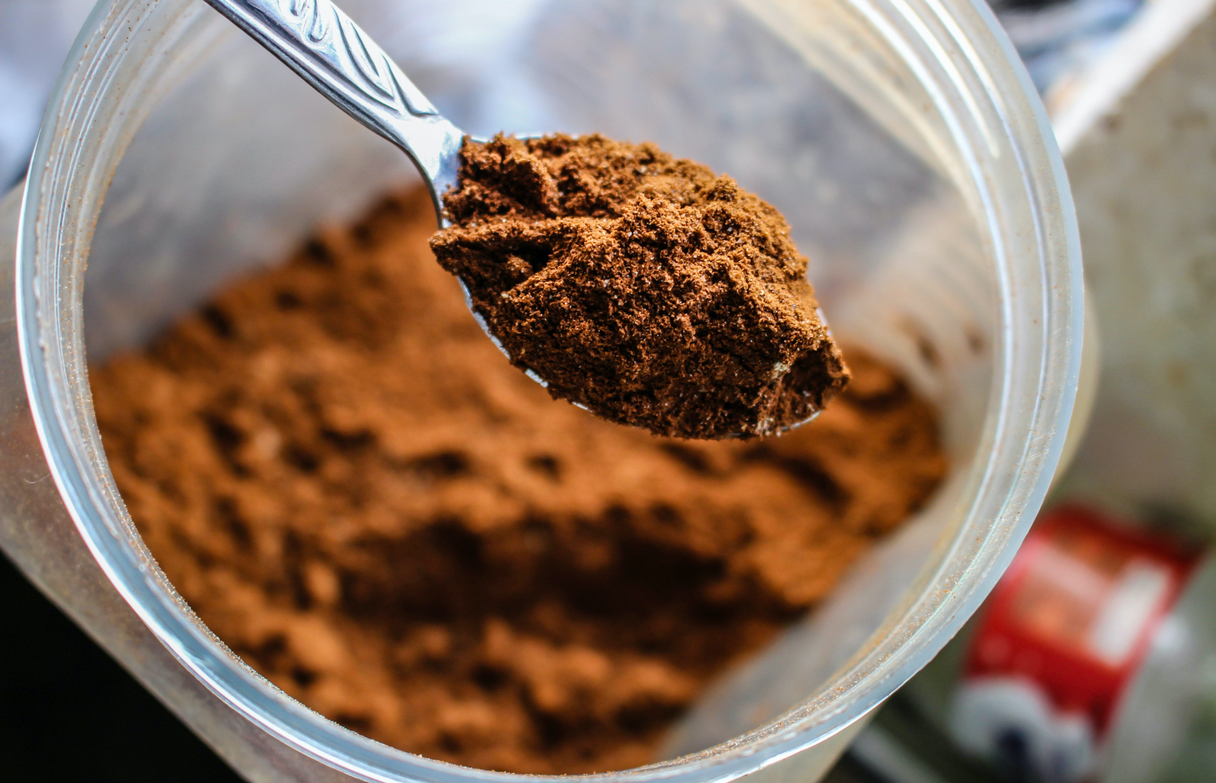 an image of cocoa powder in a clear container with a spoon holding some