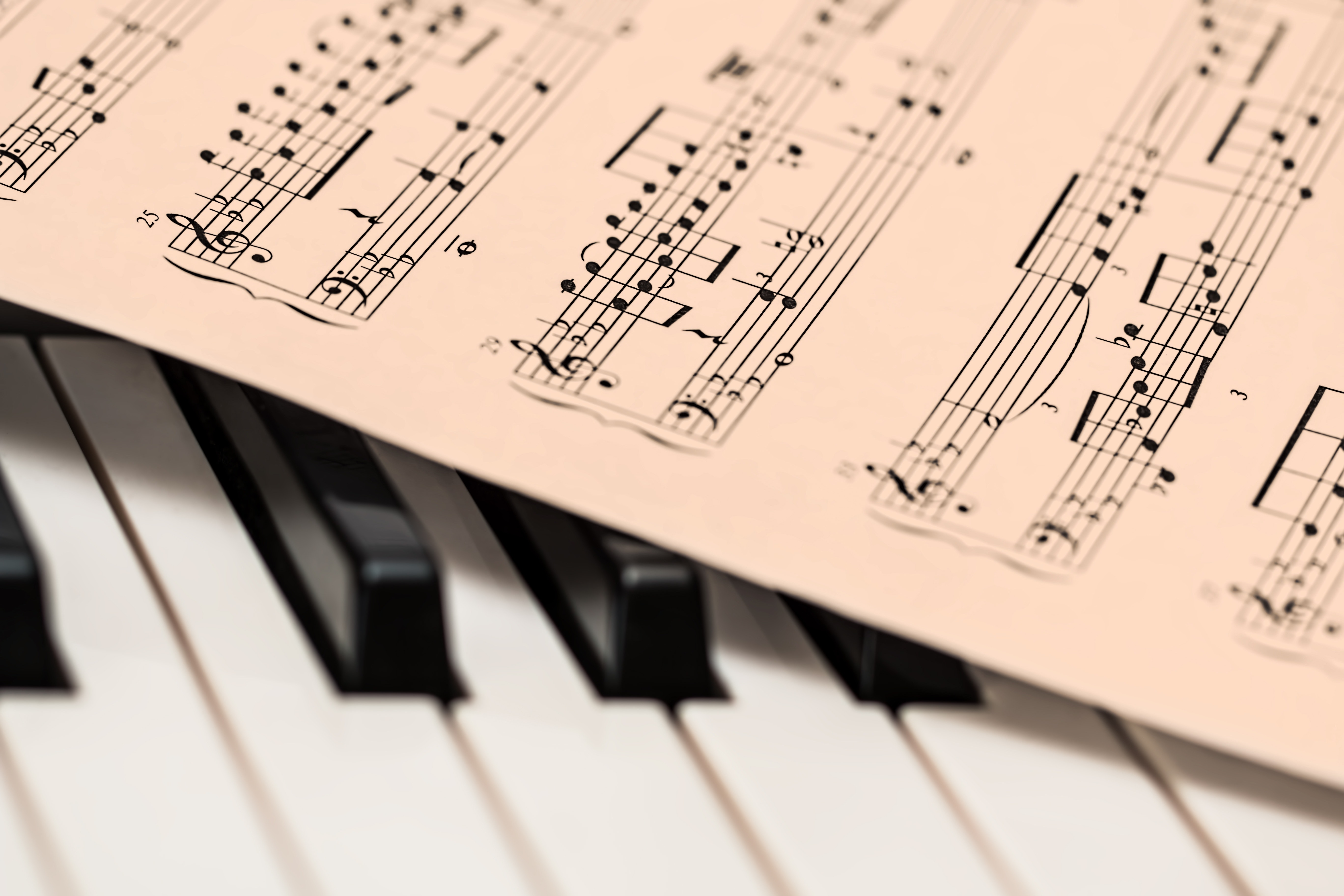 image of piano keys with an old piece of sheet music on top, probably a classical composer like Bach or Mozart