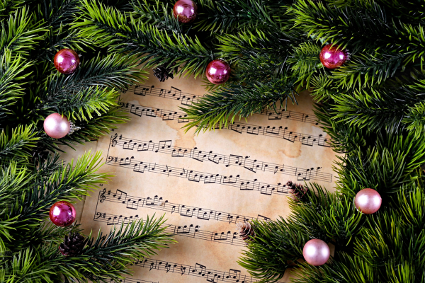 Sheet music surrounded by holiday greens and ornaments. 