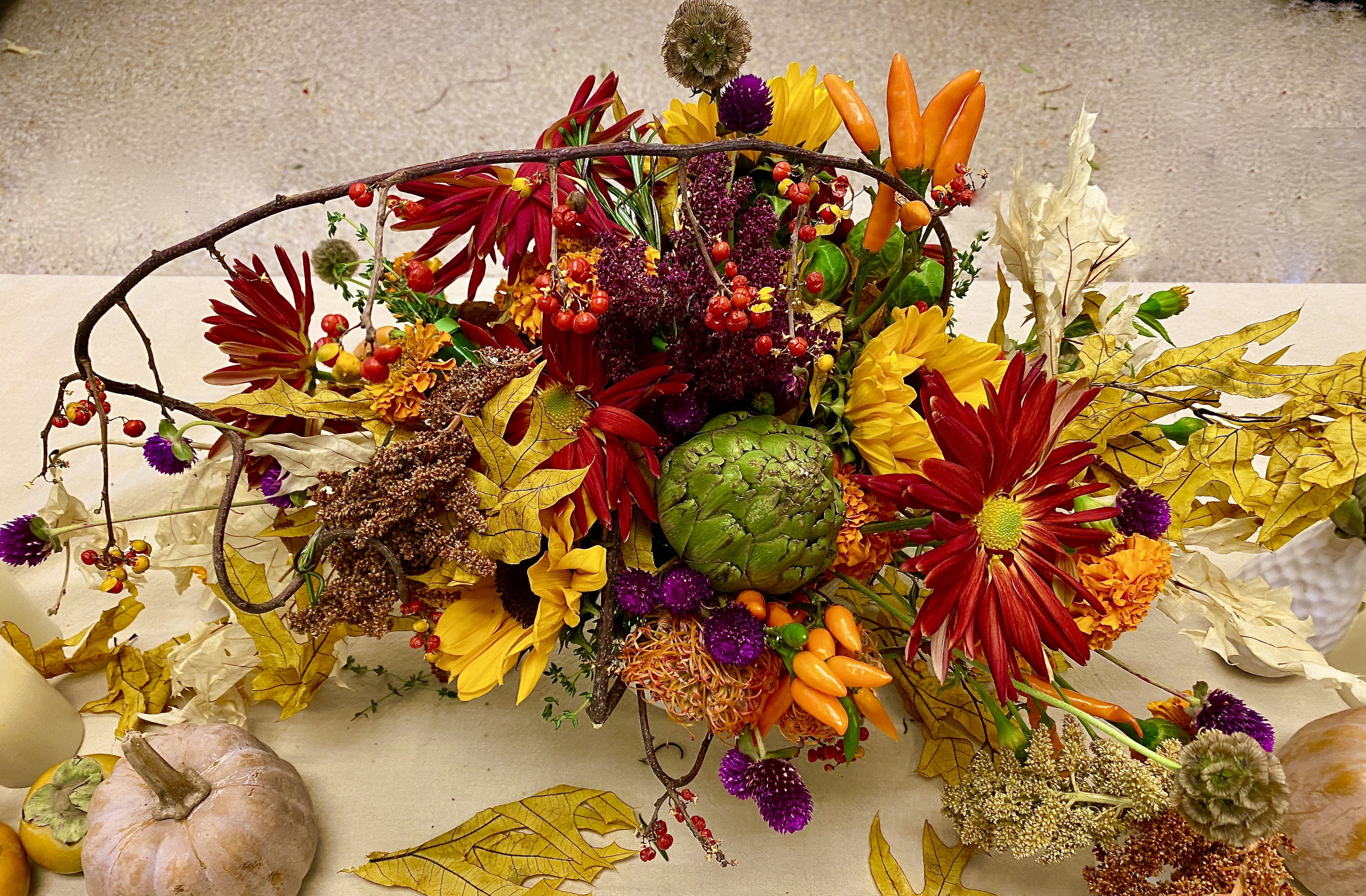 Image of a festive thanksgiving centerpiece, using florals and twigs and other unusual items