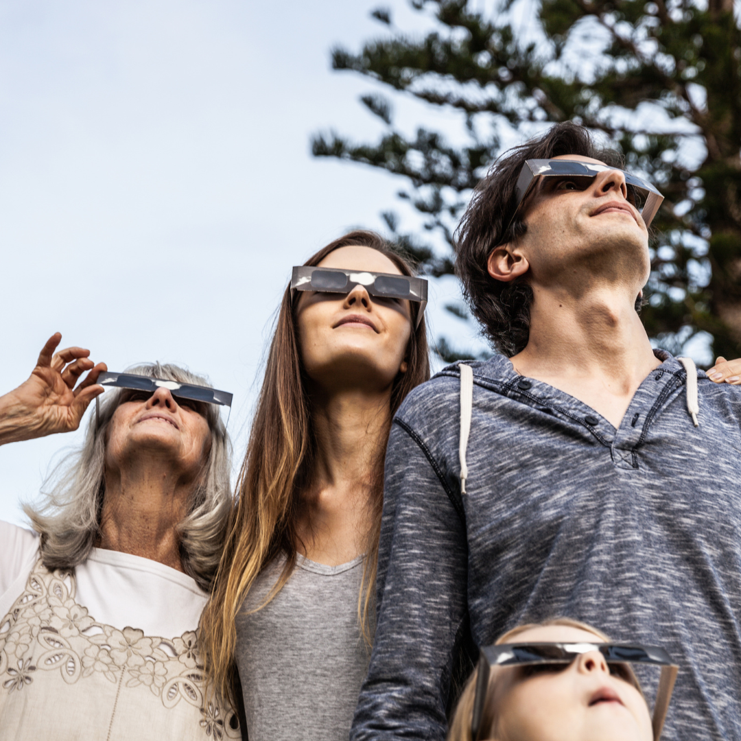 Family wearing eclipse glasses looking up at sky