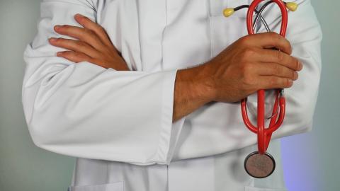 a doctor in a white lab coat holding a red stethoscope