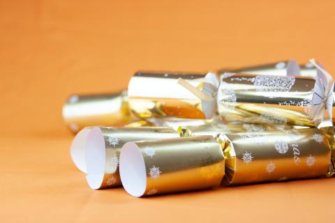 a set of golden british christmas crackers on an orange background