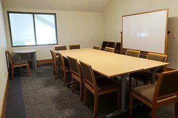A room with a table, chairs, and whiteboard.