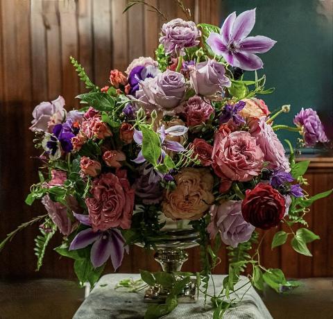 Floral arrangement of large colorful roses in a silver vase 