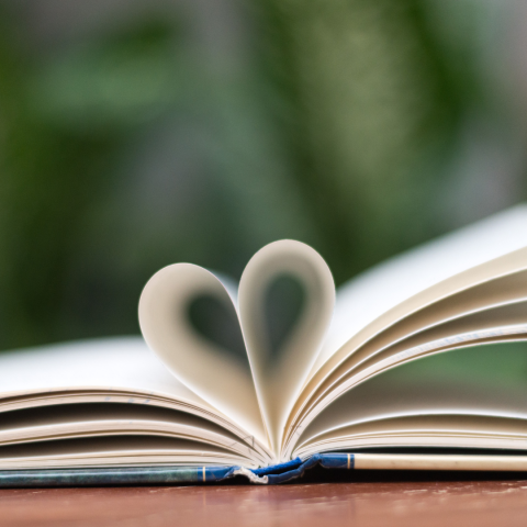 opened book with pages folded to look like heart