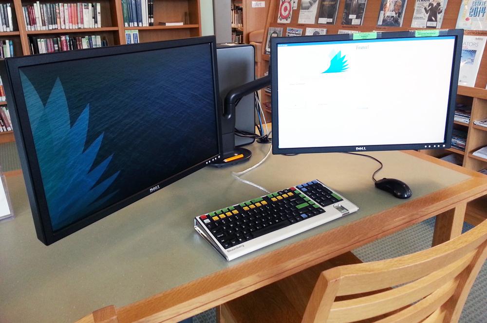 Two monitors overlook a colorful Bloomberg keyboard.
