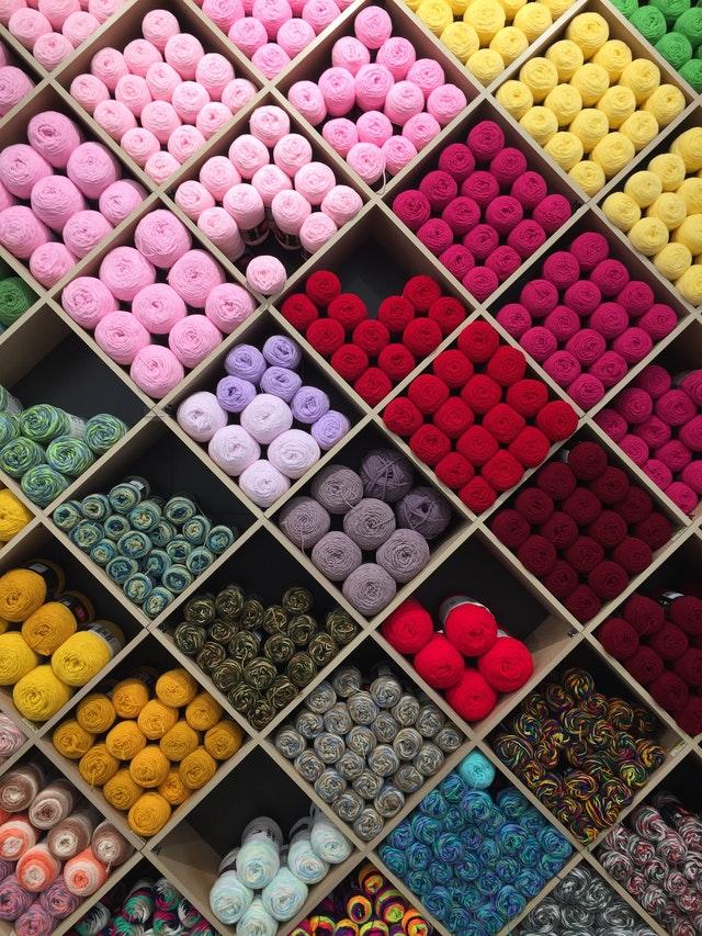 A wall of yarn skeins. The skeins are organized by color in individual boxes
