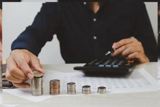 image of a person with a black shirt who is working with a pile of coins, along with a calculator