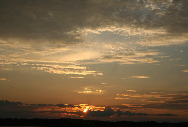 Setting sun in the horizon with a cloudy sky and dark background