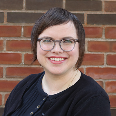 Photo of a woman in front of a brick wall.